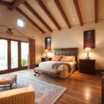 a big room with couch, bed and a ceiling with wooden beams on it