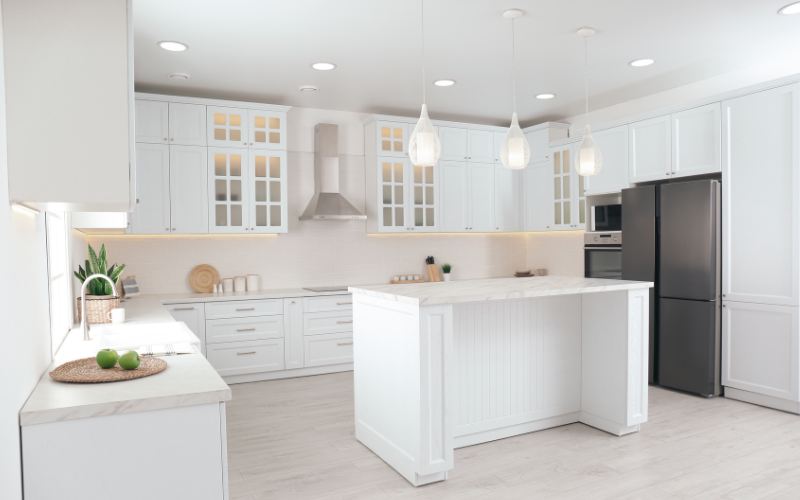 a kitchen with cabinets and island at the center with pendant lights